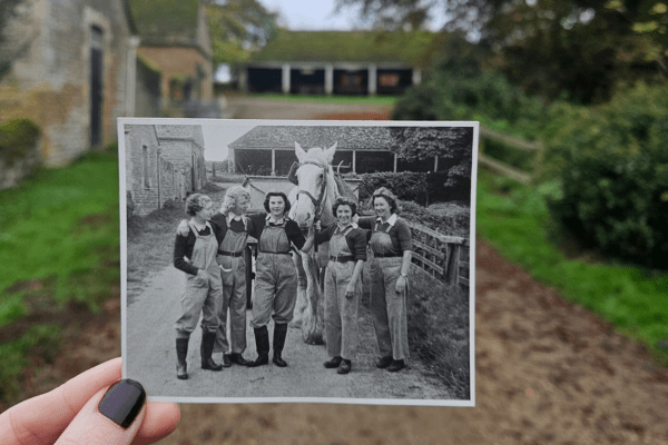 Photo shows Land army girls grouped together with a large horse at Sacrewell Farm